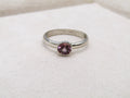 Silver ring with a pink gemstone on a white fabric background
