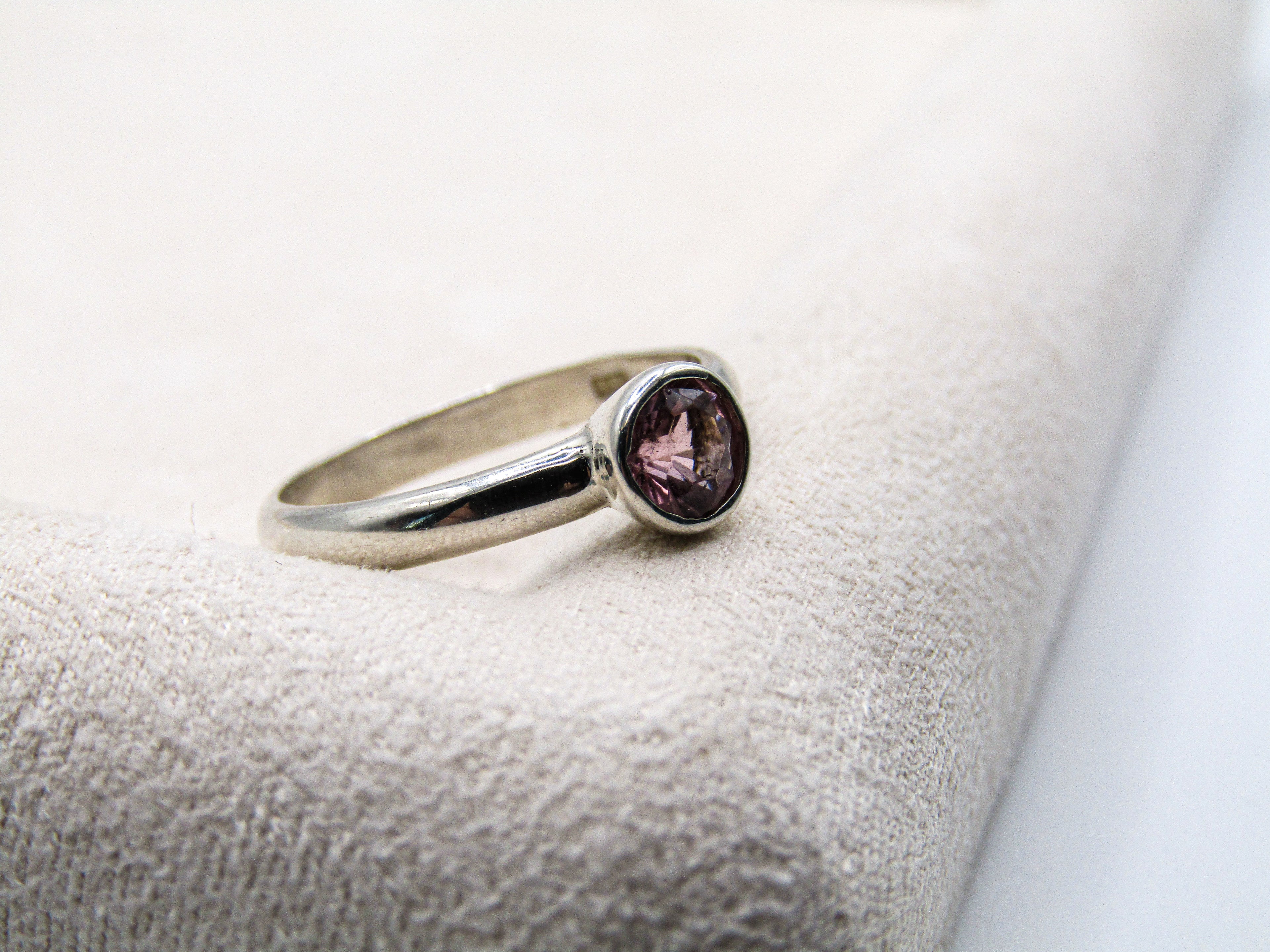 Silver ring with a purple gemstone on a textured surface