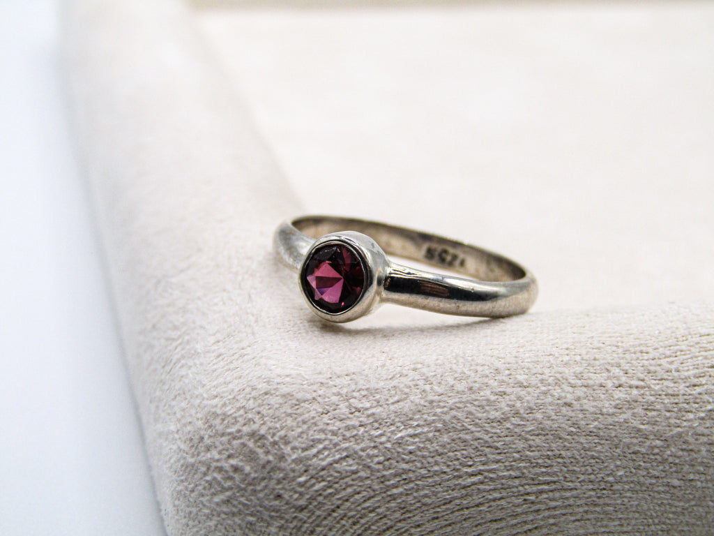 Silver ring with a red gemstone on a textured white surface