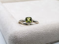 Silver ring with a green gemstone on a textured white surface