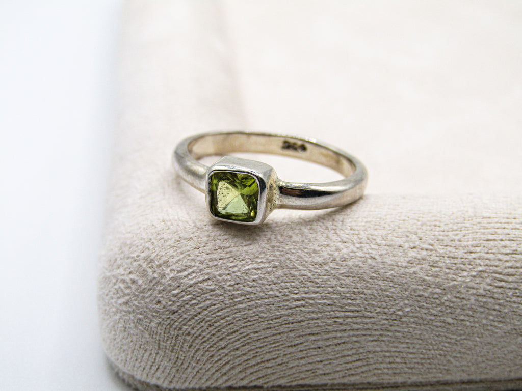 Silver ring with a green gemstone on a textured surface