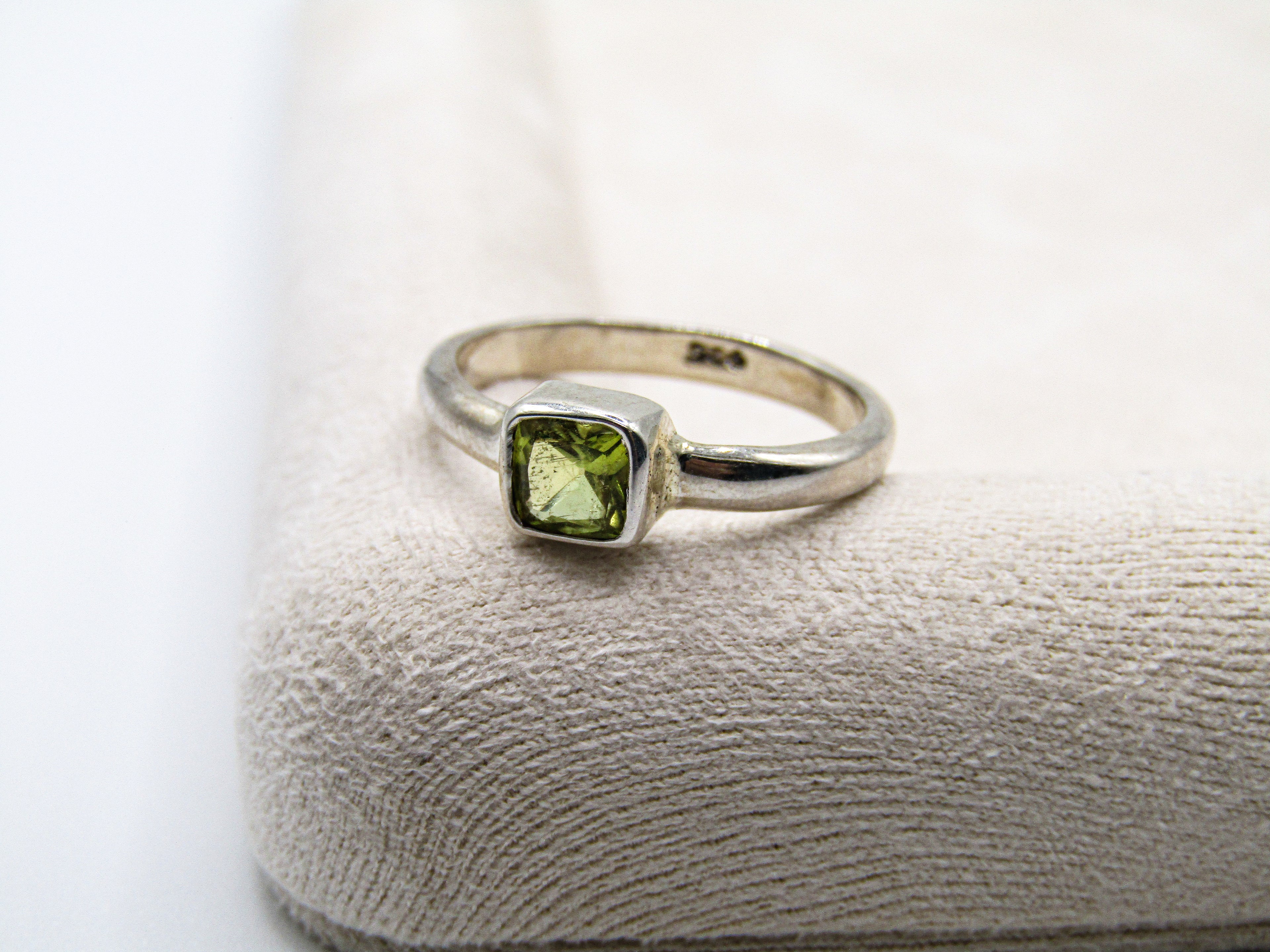 Silver ring with a green gemstone on a textured surface