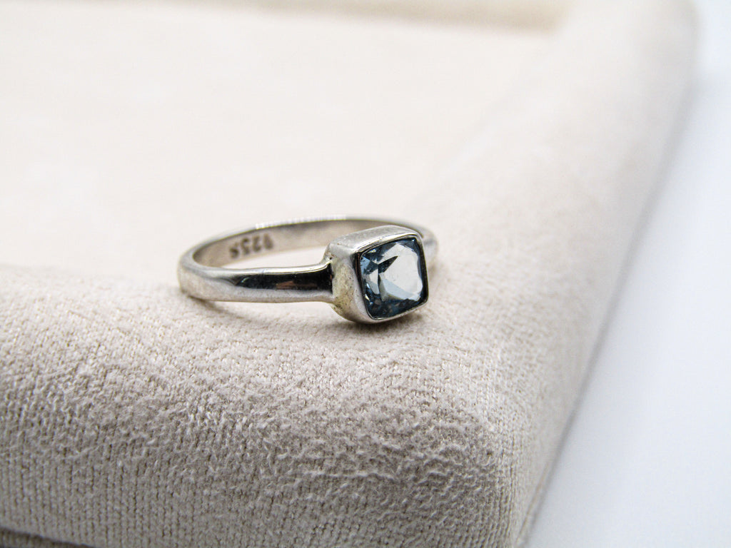 Silver ring with a blue gemstone on a textured beige surface