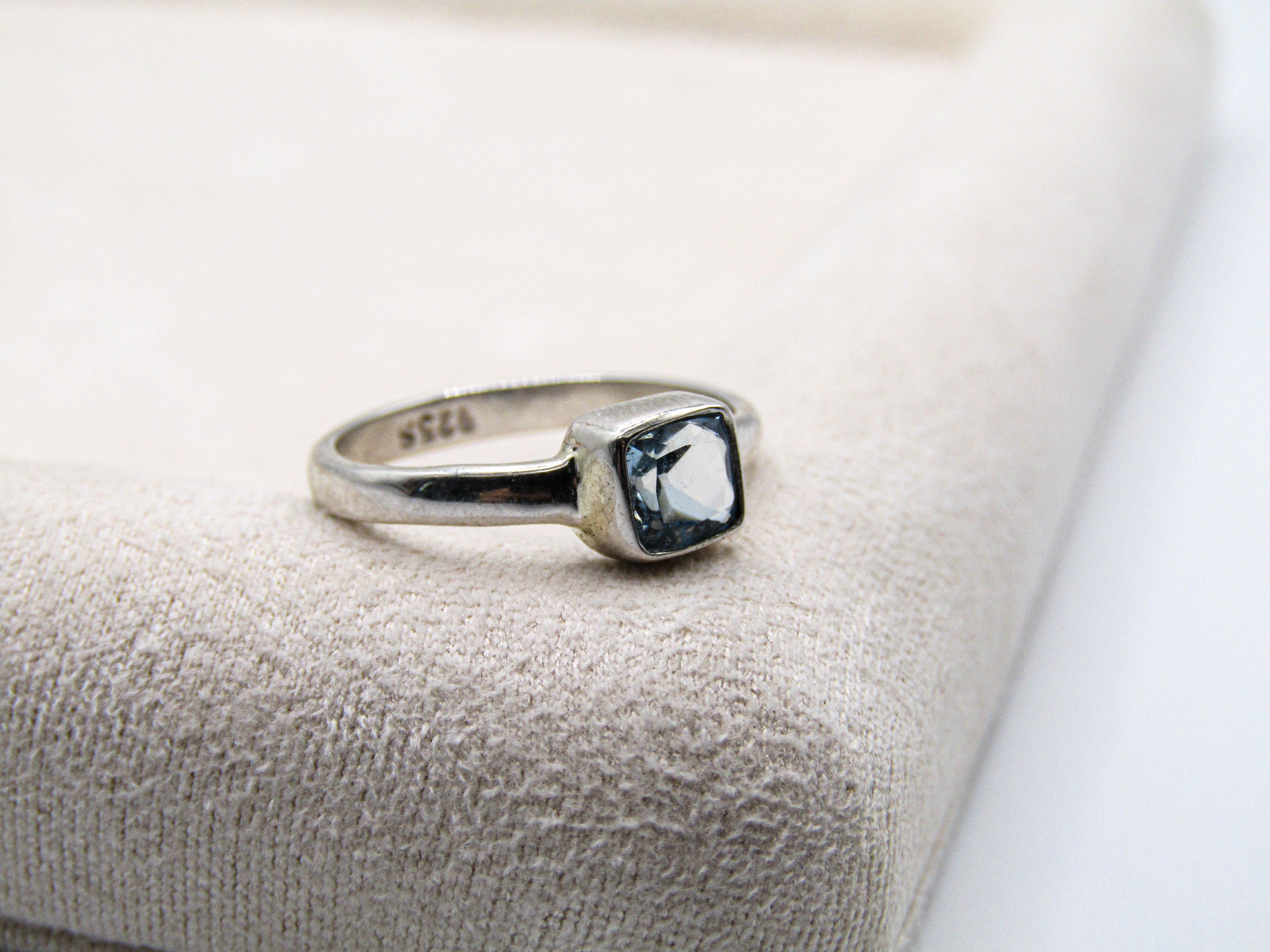 Silver ring with a blue gemstone on a textured beige surface