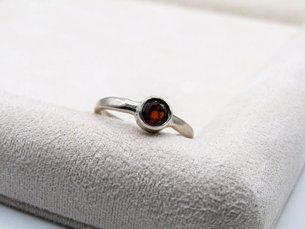 Silver ring with a red gemstone on a textured white surface
