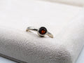 Silver ring with a red gemstone on a textured white surface