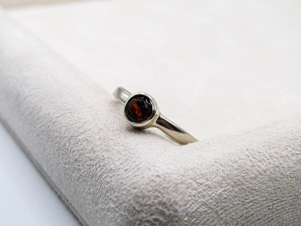 Silver ring with a red gemstone on a textured white surface
