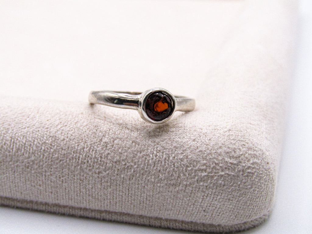 Silver ring with a red gemstone on a textured white surface