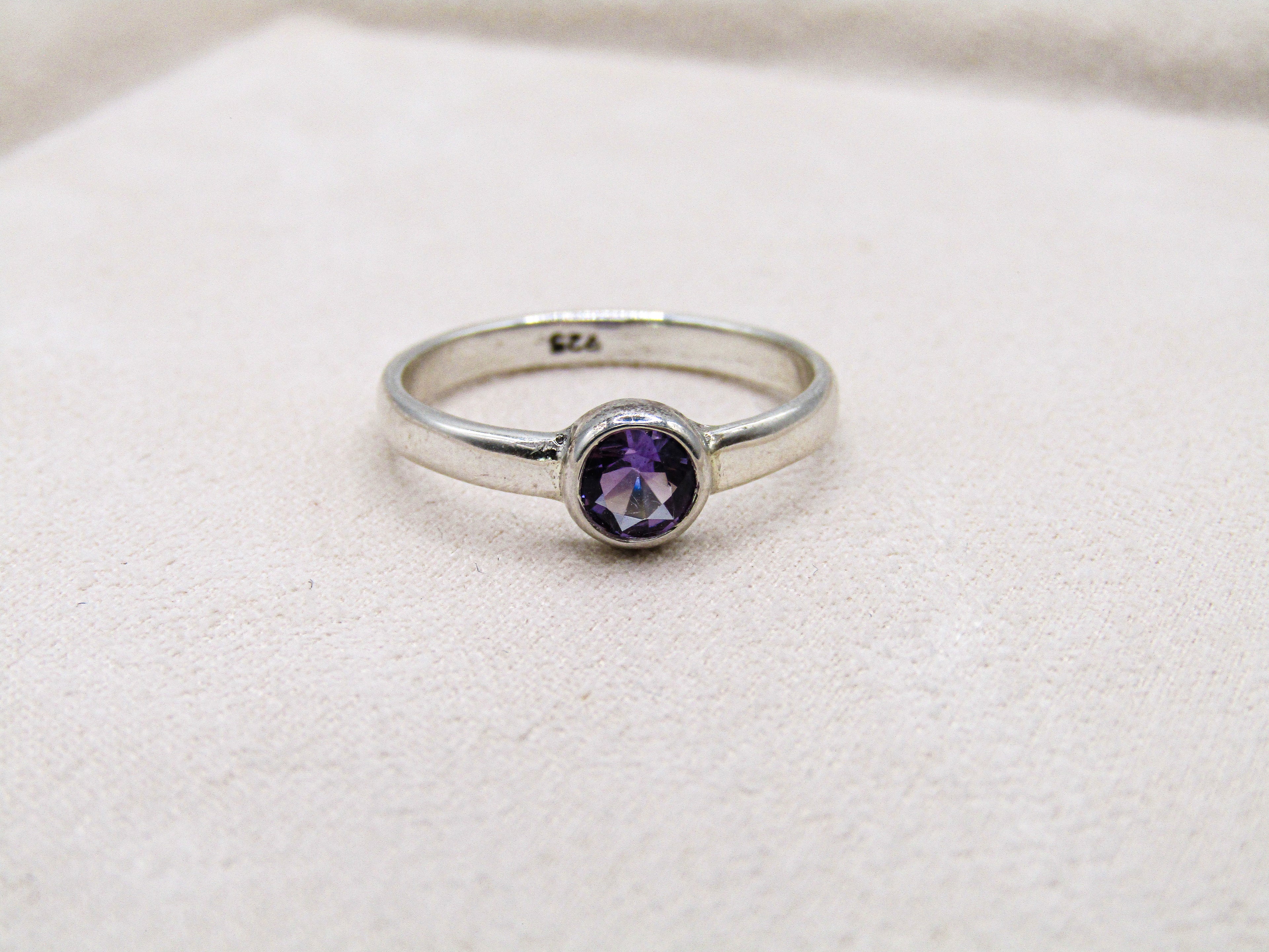 Silver ring with a purple gemstone on a white background