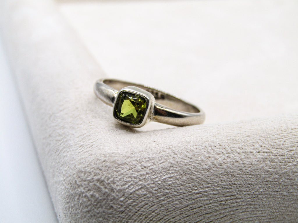 Silver ring with a green gemstone on a textured white surface