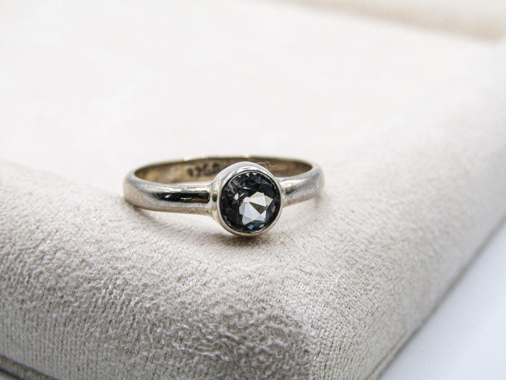 Silver ring with a black gemstone on a textured surface