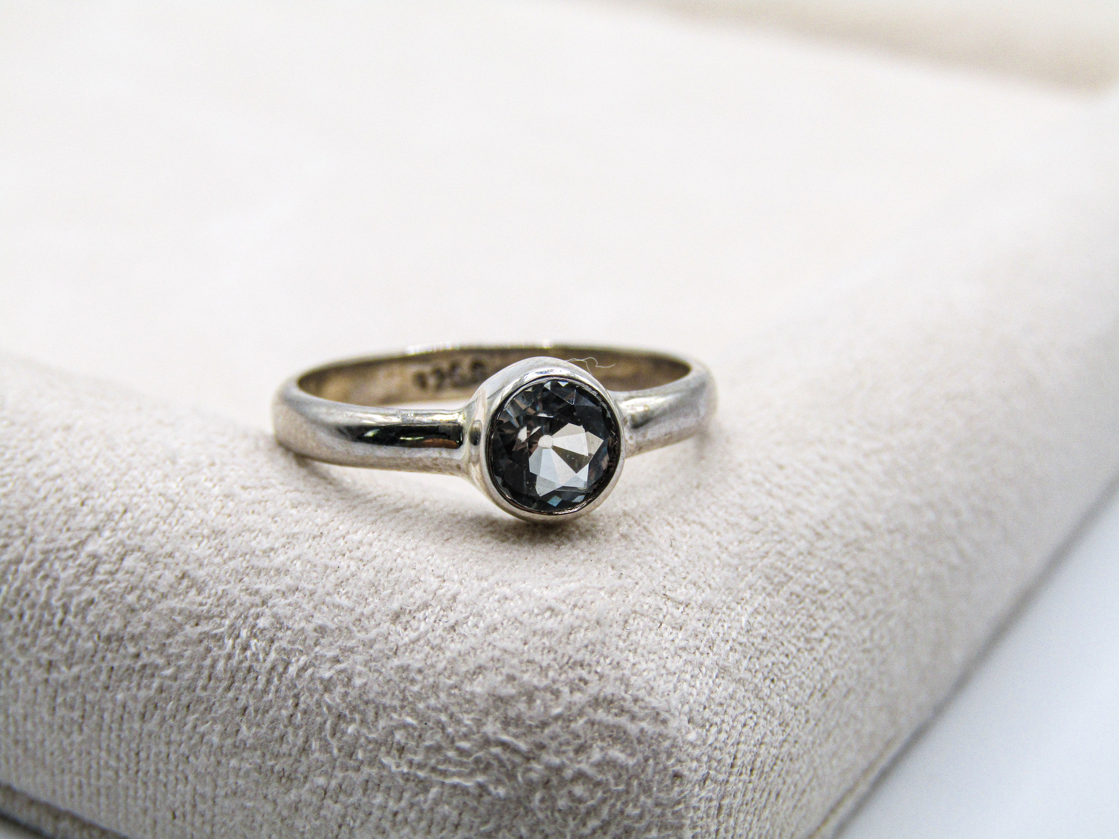 Silver ring with a black gemstone on a textured surface