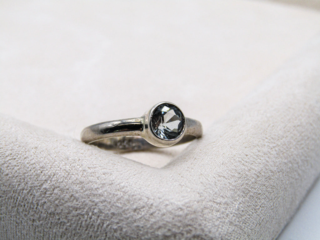 Silver ring with a black gemstone on a white cushion