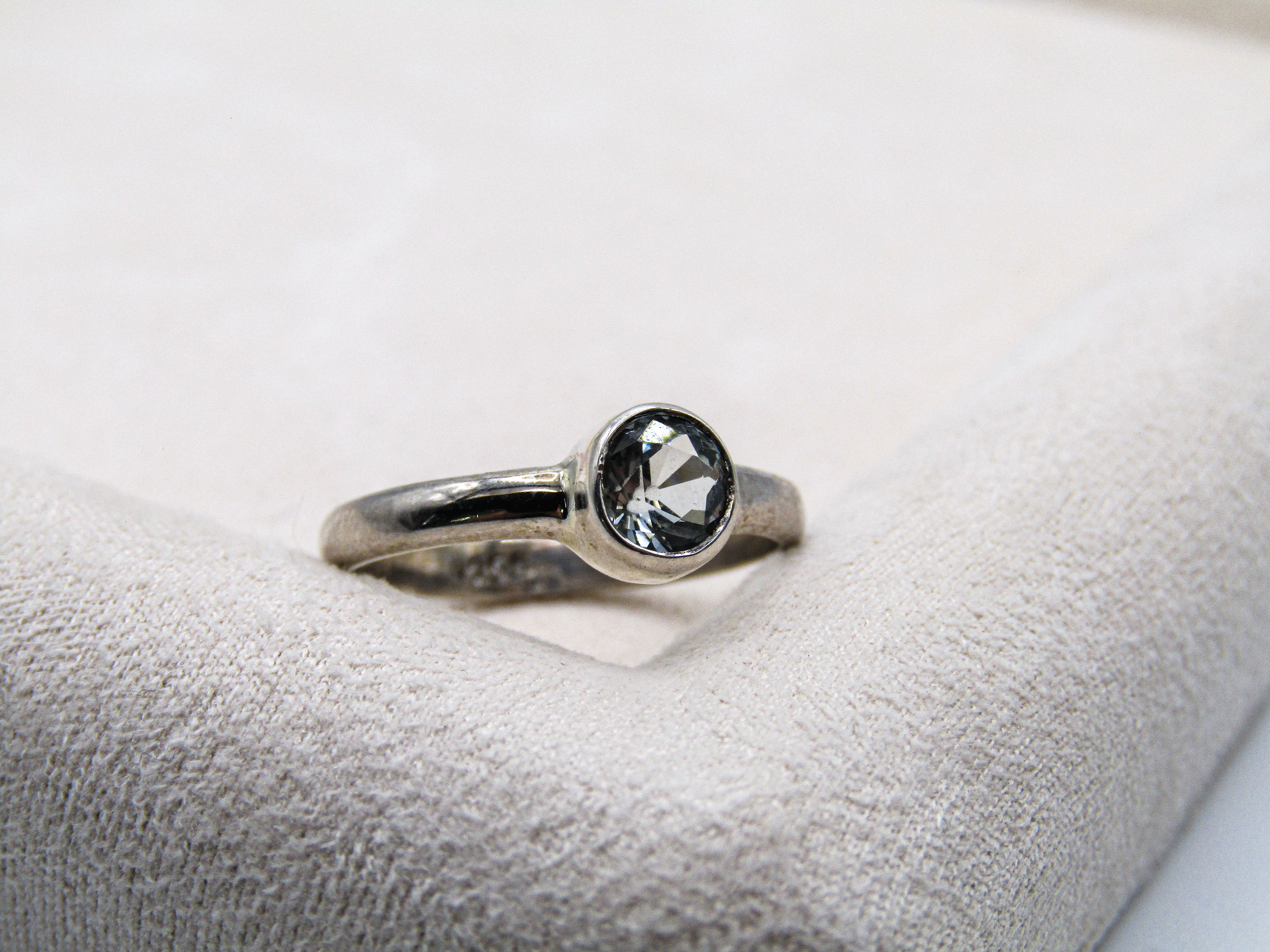 Silver ring with a black gemstone on a white cushion