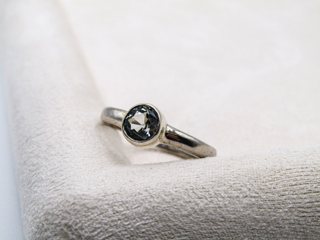 Silver ring with a black gemstone on a textured white surface