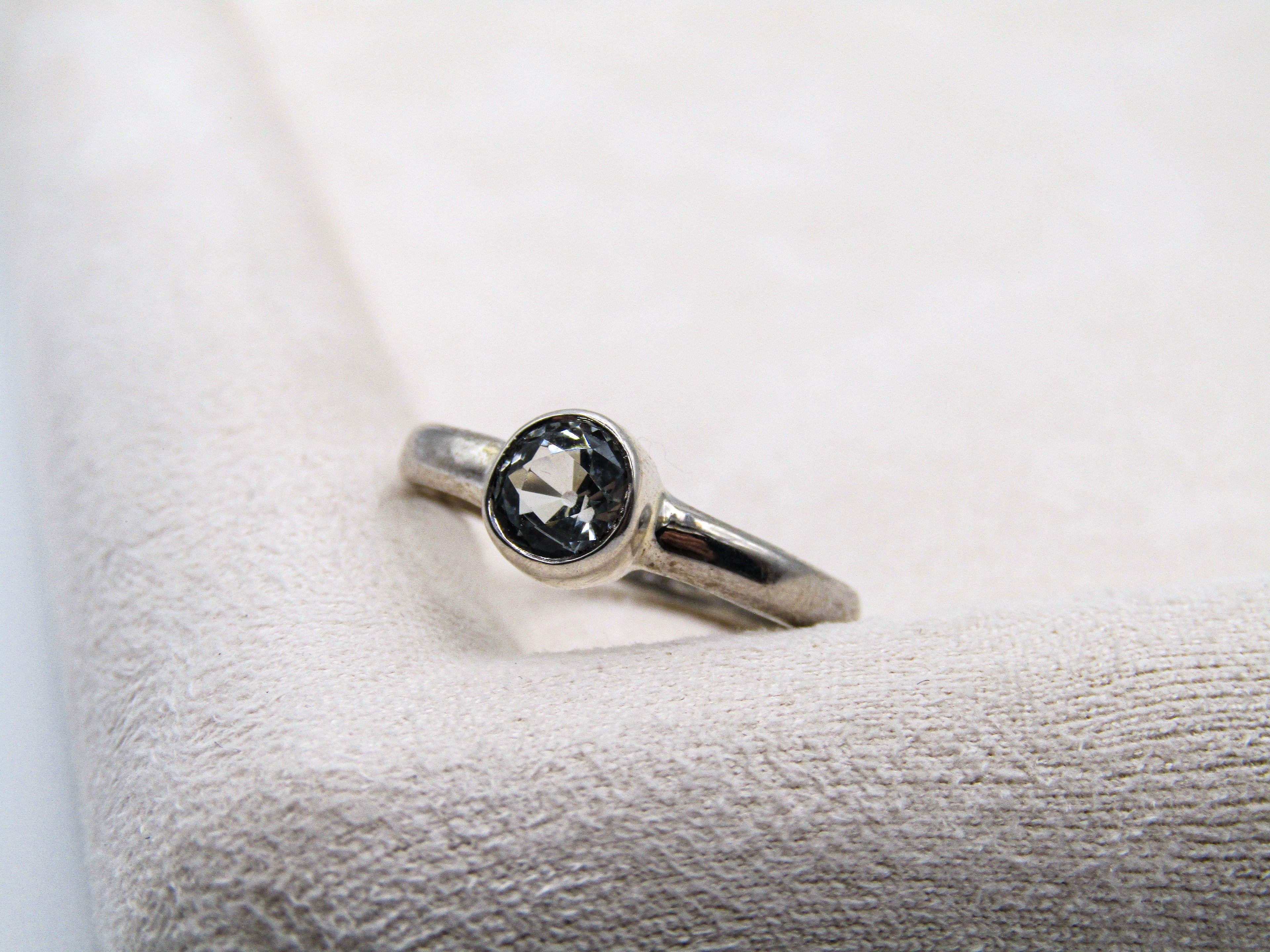 Silver ring with a black gemstone on a textured white surface