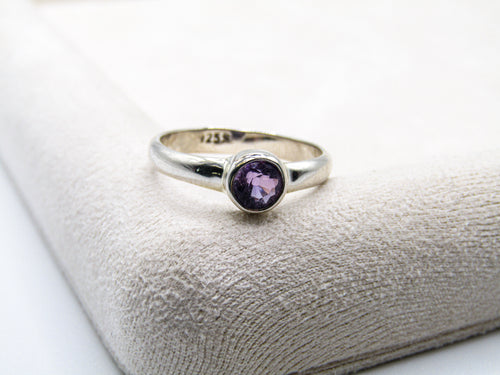 Silver ring with a purple gemstone on a textured surface