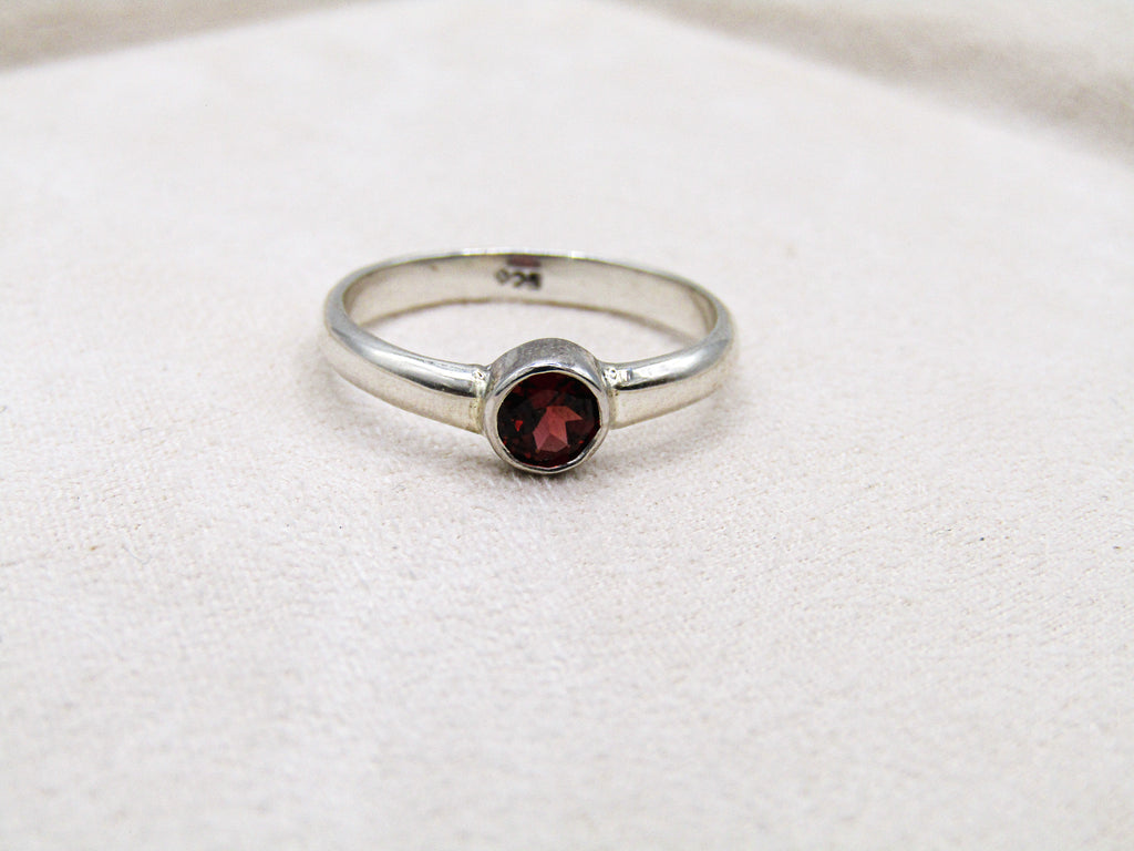 Silver ring with a red gemstone on a white fabric background