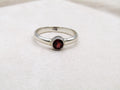Silver ring with a red gemstone on a white fabric background