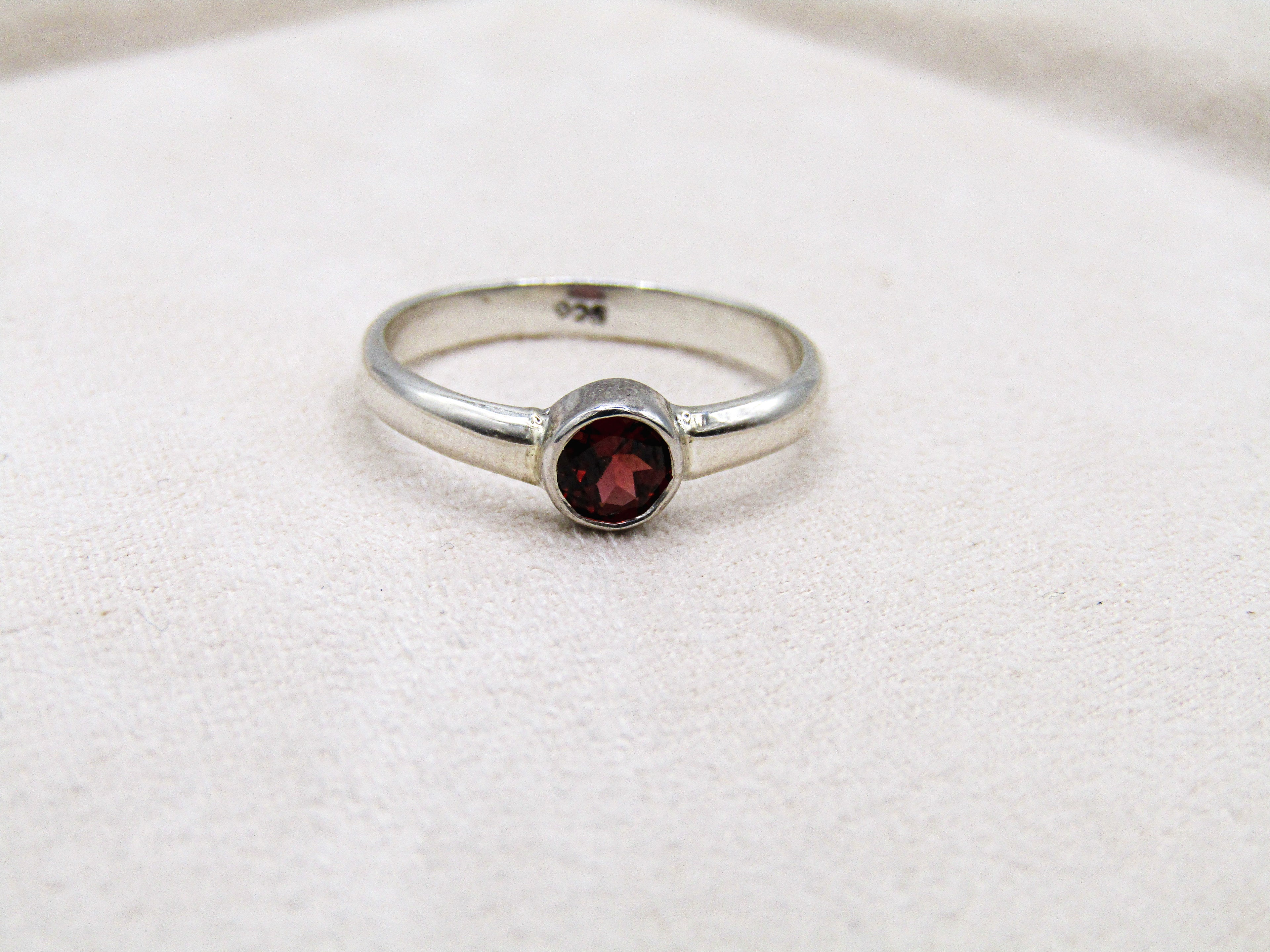 Silver ring with a red gemstone on a white fabric background